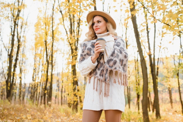 Jolie jeune femme avec une tasse de café dans le parc en automne