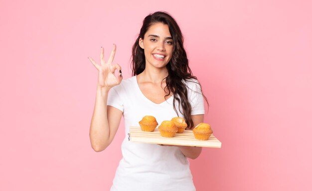 Jolie jeune femme tenant un plateau à muffins