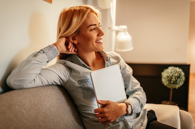 Jolie jeune femme tenant une tablette à la maison