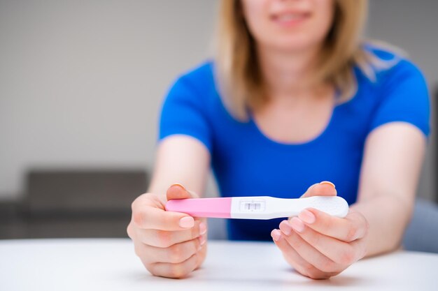 Photo jolie jeune femme tenant un test de grossesse positif attendant un bébé
