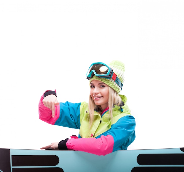 Jolie jeune femme en tenue de ski s'asseoir près de snowboard