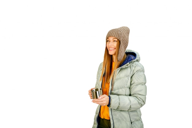 Jolie jeune femme touriste dans des vêtements d'hiver avec une boisson savoureuse chaude isolée sur blanc.