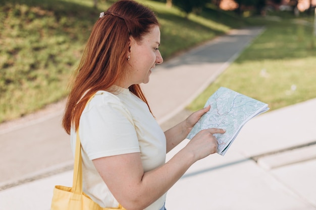 Jolie jeune femme touriste explore la nouvelle ville Heureuse femme rousse avec carte dans les mains