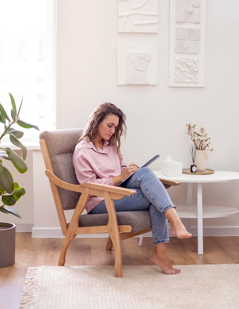 Jolie jeune femme travaillant assise à la maison sur une chaise