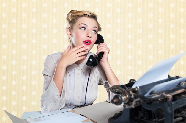 Jolie jeune femme travaillant sur une machine à écrire vintage