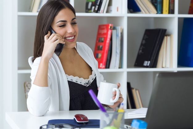 Jolie jeune femme travaillant avec un ordinateur portable dans son bureau.