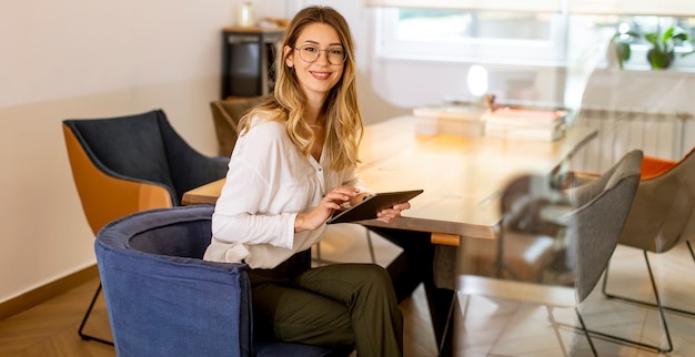 Jolie jeune femme travaillant avec une tablette numérique au bureau