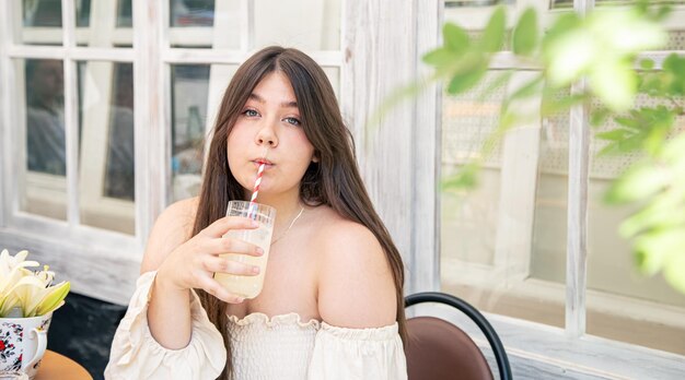 Jolie jeune femme avec un verre de limonade sur la terrasse du café