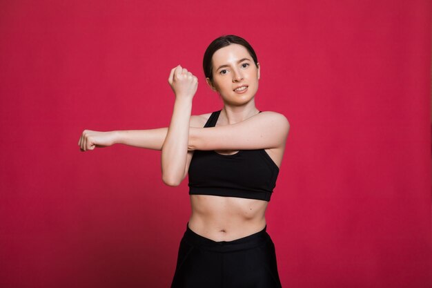 jolie jeune femme en vêtements de sport étirant les muscles avant de s'entraîner sur le rouge