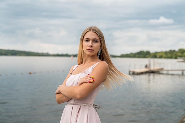 Jolie jeune femme vêtue d'une robe de soirée de mode rose posant près du lac dans le parc