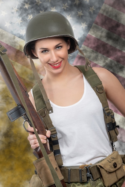 Jolie jeune femme vêtue de l&#39;uniforme militaire de la seconde guerre mondiale avec casque et fusil