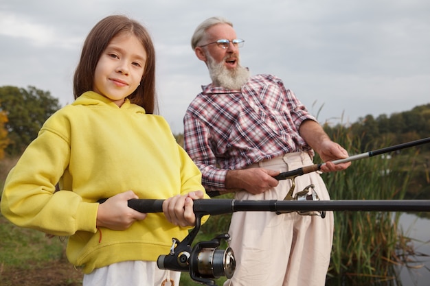 Jolie jeune fille appréciant l'apprentissage de la pêche de son grand-père