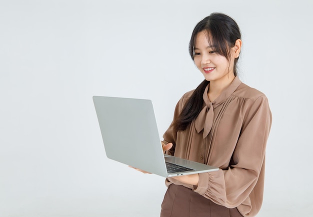 Une jolie jeune fille asiatique aime taper sur un ordinateur portable avec le sourire et est heureuse de le porter comme un ordinateur portable confortable pour la communication et l'amusement en ligne. Mode de vie moderne du travail des entreprises via Internet.