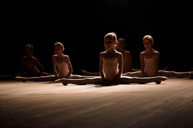 Jolie jeune fille assise sur scène ayant des étirements et une formation pour les danses de ballet.