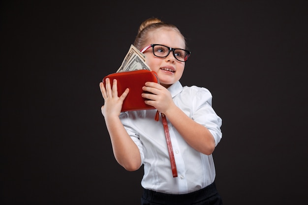 Jolie jeune fille en chemise blanche et pantalon noir tient un sac à main rouge