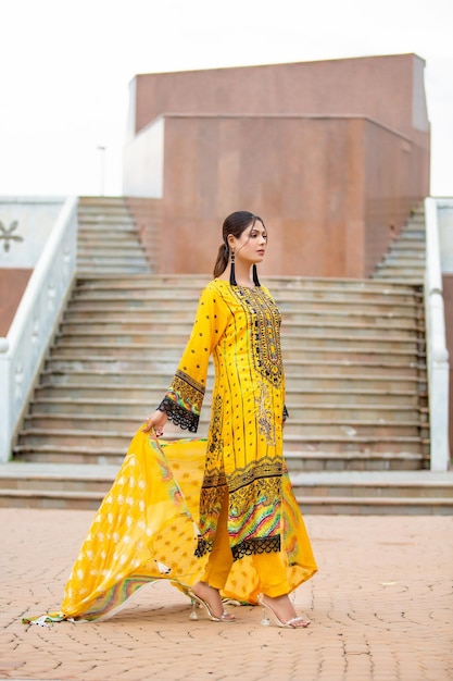 Jolie jeune fille côté pose montrant sa robe jaune complète pour une séance photo de mode en plein air