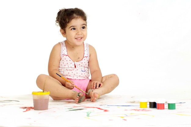 Une jolie jeune fille dessine une peinture assise sur le sol