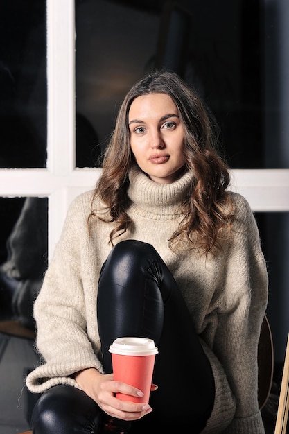 Jolie jeune fille est assise sur une chaise en pantalon de cuir