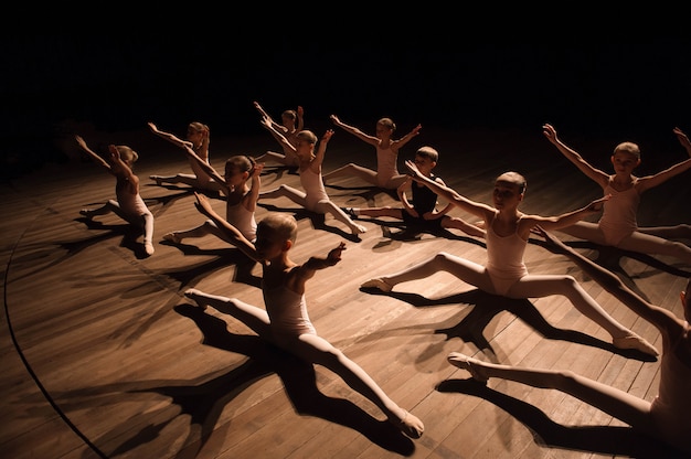 Jolie jeune fille et garçon assis sur scène ayant des étirements et une formation pour la danse classique.