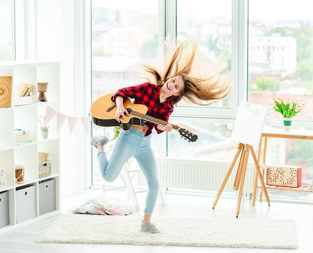 Jolie Jeune Fille Avec Guitare En Saut En Hauteur à La Maison