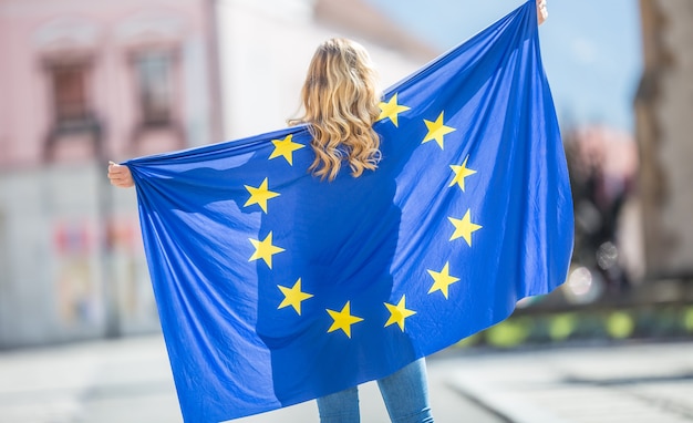 Jolie jeune fille heureuse avec le drapeau de l'Union européenne.