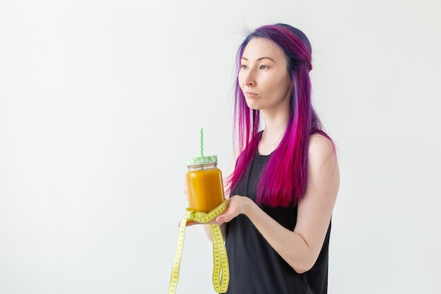 Jolie jeune fille hipster métisse aux cheveux colorés boit un smoothie aux fruits avant de commencer un yoga