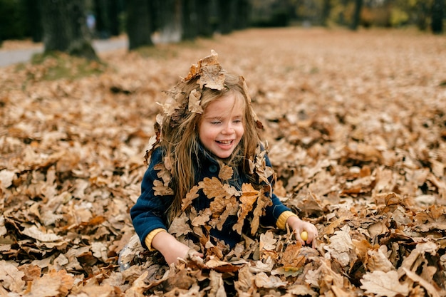 Une jolie jeune fille jouant dans les feuilles