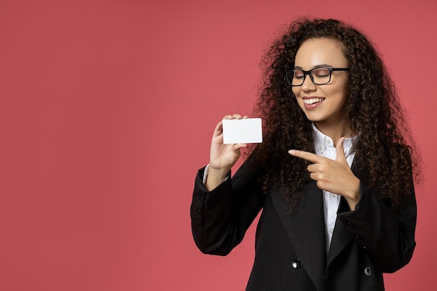 Jolie jeune fille à lunettes et un costume noir sur fond rouge