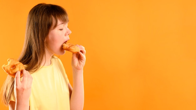 Photo jolie jeune fille mangeant des beignets avec espace copie