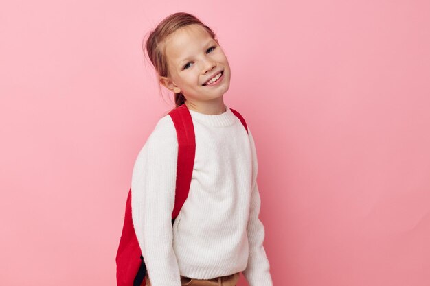 Jolie jeune fille avec une planche à roulettes à la main fond rose