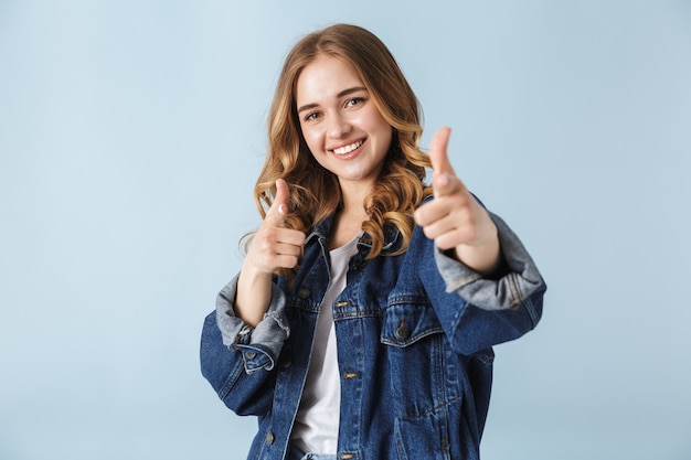 Jolie jeune fille portant des vêtements décontractés debout isolé sur blanc, pointant du doigt