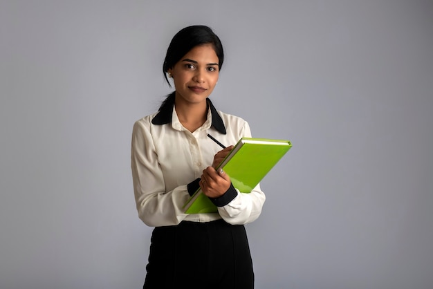 Jolie jeune fille posant avec le livre sur fond gris