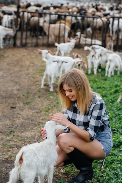 Une jolie jeune fille pose dans un ranch avec des chèvres et d'autres animaux. Agriculture, élevage.