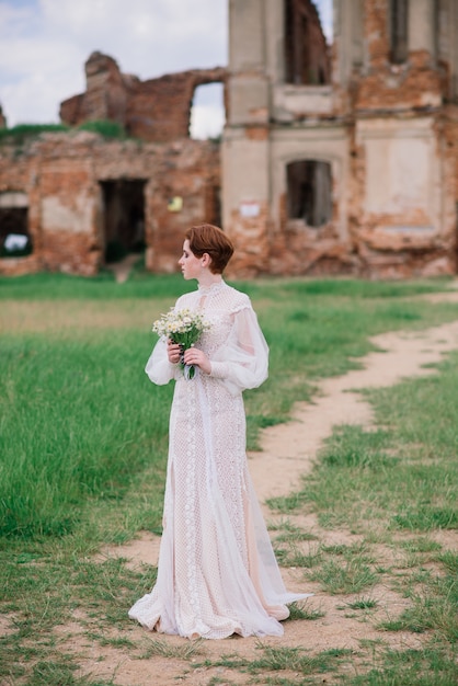 Jolie jeune fille rousse caucasienne dans un jardin et à l'extérieur avec son bouquet de mariée. Belle mariée rousse.