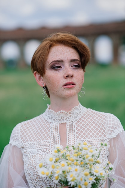 Jolie jeune fille rousse caucasienne dans un jardin et à l'extérieur avec son bouquet de mariée. Belle mariée rousse.