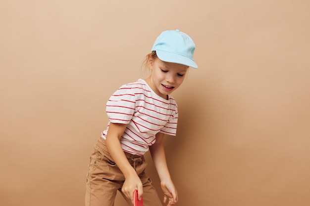 Jolie jeune fille skateboard à la main posant des vêtements de bébé amusant fond isolé