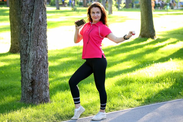 Jolie jeune fille sportive écoutant de la musique lors d'une promenade