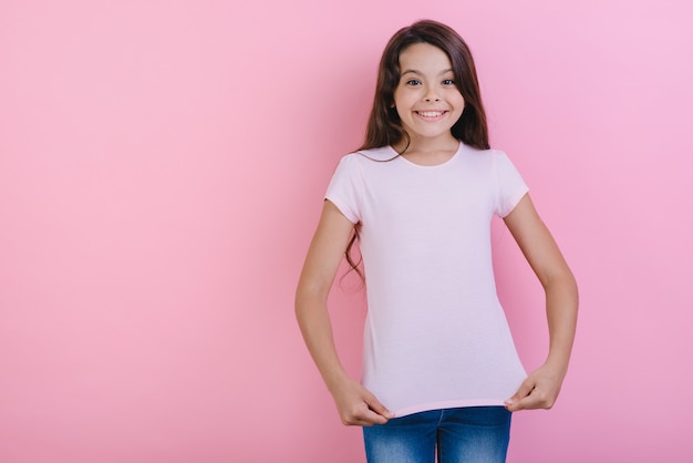 Jolie Jeune Fille Sur Studiotouches Rose Son T-shirt En Regardant La Caméra.