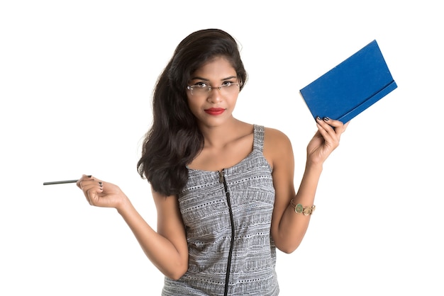 Jolie jeune fille tenant un livre et posant sur un mur blanc