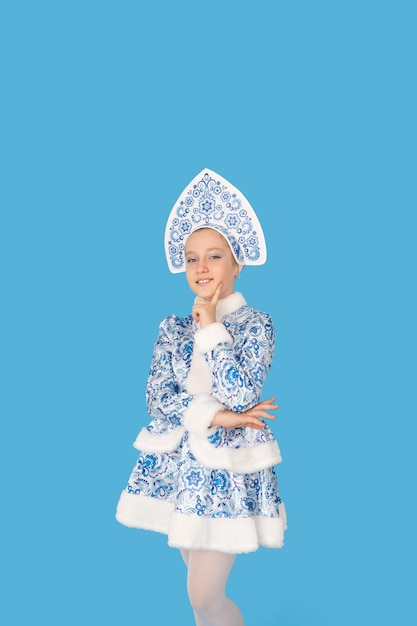 Jolie jeune fille vêtue d'un costume bleu de jeune fille des neiges souriant. Isolé sur fond bleu