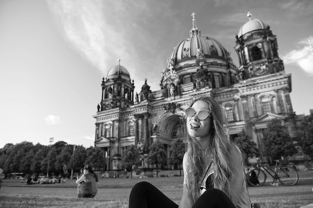 Jolie jeune gil assise devant la cathédrale de Berlin au beau coucher de soleil et mange du chocolat