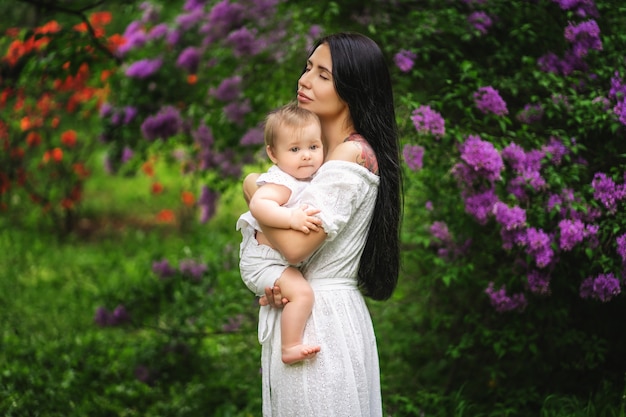 Jolie jeune mère tenant son bébé dans un jardin fleuri