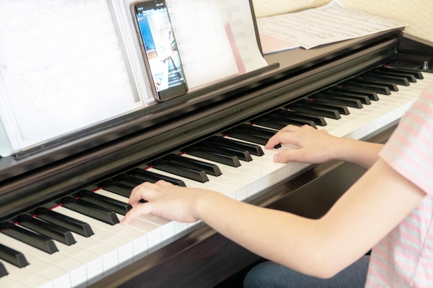 Jolie jeune musicien jouant du piano numérique classique à la maison pendant les cours en ligne à la maison, distance sociale pendant la quarantaine, auto-isolement, concept d'éducation en ligne