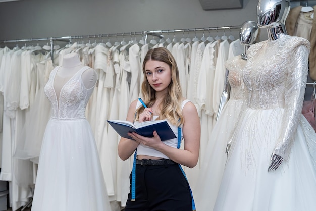 Jolie jeune vendeuse tient un journal de notes dans un magasin de mariage moderne