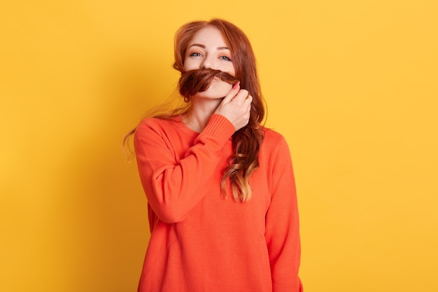 Jolie jolie jeune femme faisant la moustache avec ses cheveux et regardant avec un sourire charmant