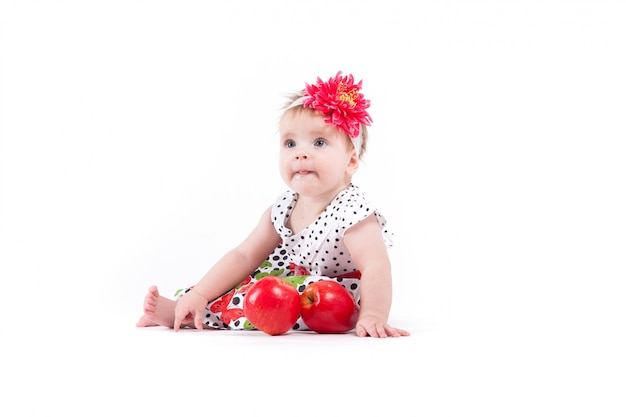 Jolie jolie petite fille en robe papillon près de pommes rouges