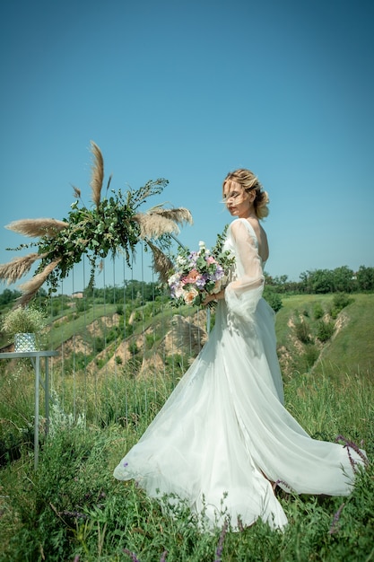 Une jolie mariée, une blonde dans une belle robe chère, marchant parmi la nature et de beaux paysages