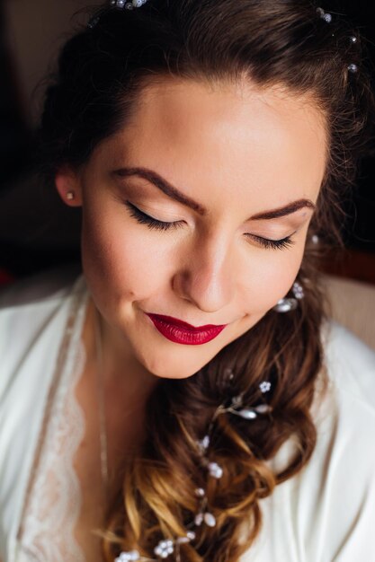 La jolie mariée a fermé les yeux et sur son visage est une belle coiffure de maquillage doux avec des ornements de cheveux