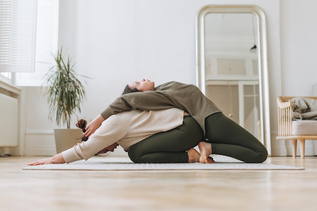 Jolie mère femme d'âge moyen et fille adolescente ptactice yoga ensemble dans la salle lumineuse