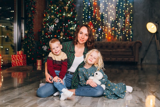 Jolie mère avec fille et fils posant à l'arbre de Noël